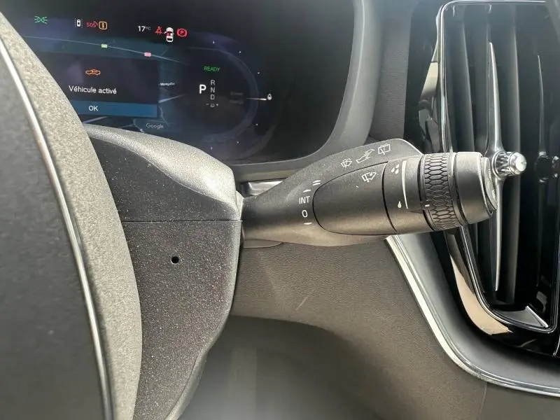 Gros plan sur la commande des essuie-glaces à droite du volant dans le tableau de bord gris du Volvo XC60 2024.