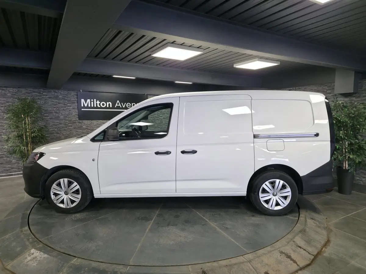 Vue de profil côté gauche d’un utilitaire Volkswagen Caddy Cargo blanc avec portes coulissantes et jantes acier.