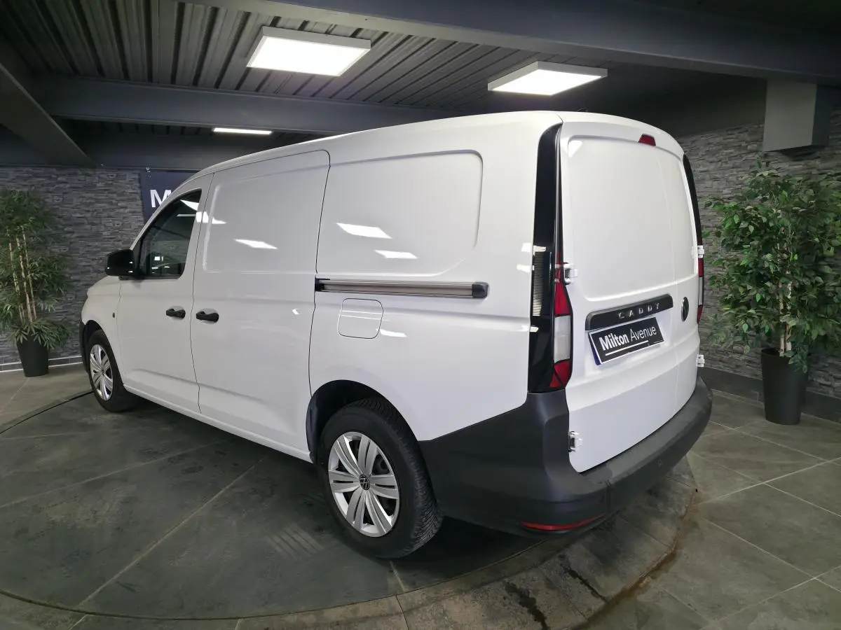 Vue 3/4 arrière droite du Volkswagen Caddy Cargo blanc, fourgon avec portes arrière battantes et pare-chocs noir.