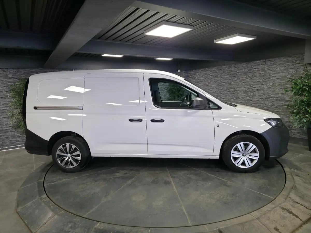 Vue latérale droite d'un Volkswagen Caddy Cargo blanc 2023 avec portes coulissantes et jantes acier.