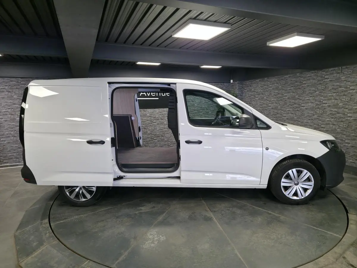 Vue latérale droite d’un Volkswagen Caddy Cargo blanc 2023 avec porte coulissante ouverte et jantes alliage.