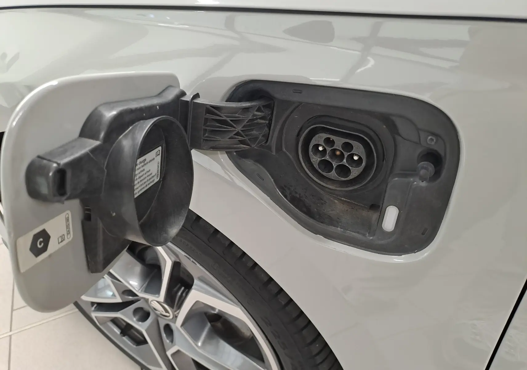 Gros plan sur la trappe de recharge ouverte côté gauche d’une Skoda Octavia Combi gris perle avec jante alliage 19'' anthracite.