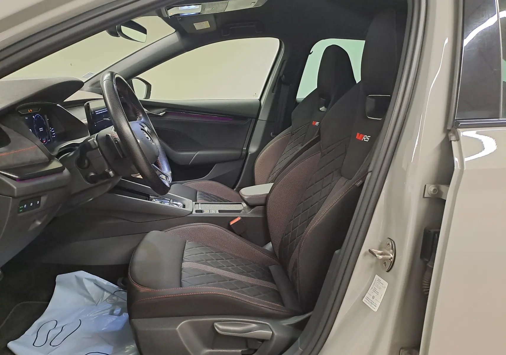 Vue intérieure côté conducteur de la Skoda Octavia Combi gris perle 2021, sièges sport RS avec surpiqûres rouges.