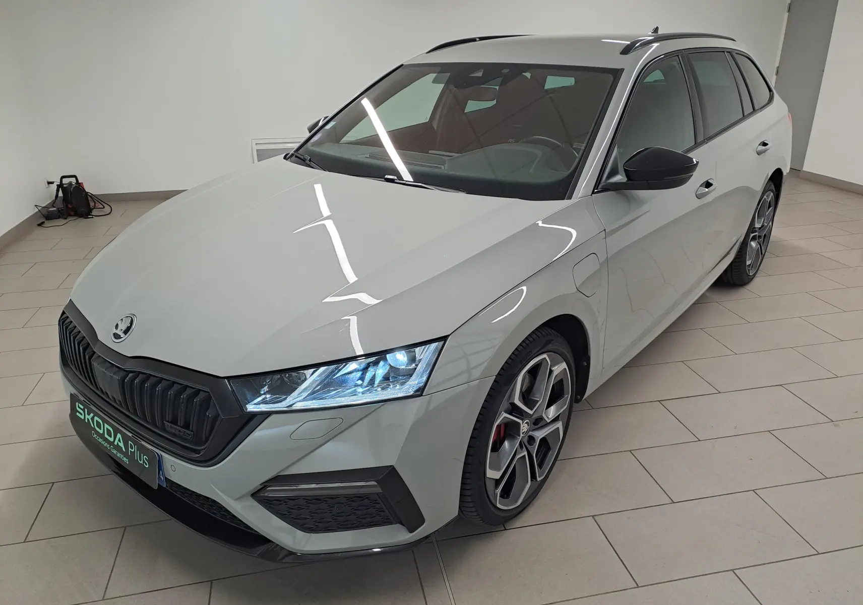 Vue 3/4 avant droite d'une Skoda Octavia Combi gris perle avec jantes alliage 19'' anthracite polies et phares allumés.