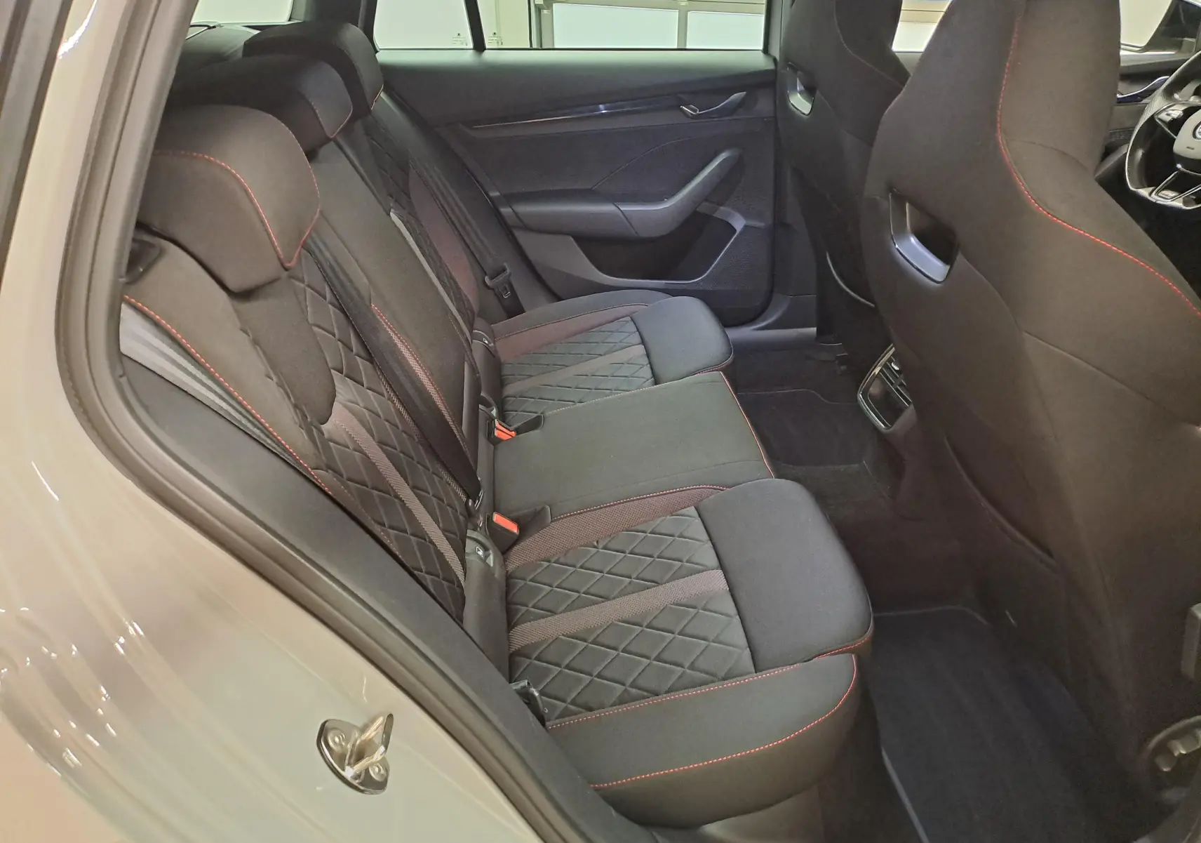Vue intérieure côté gauche des sièges arrière en tissu noir avec surpiqûres rouges du Skoda Octavia Combi gris perle 2021.