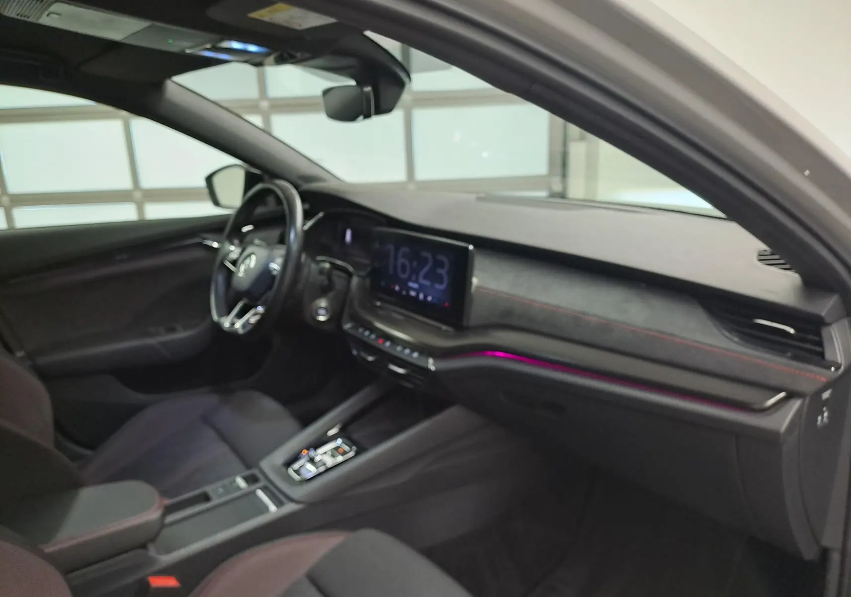Vue intérieure côté conducteur de la Skoda Octavia Combi 1.4 TSI PHEV 2021 avec tableau de bord noir et éclairage d’ambiance violet.