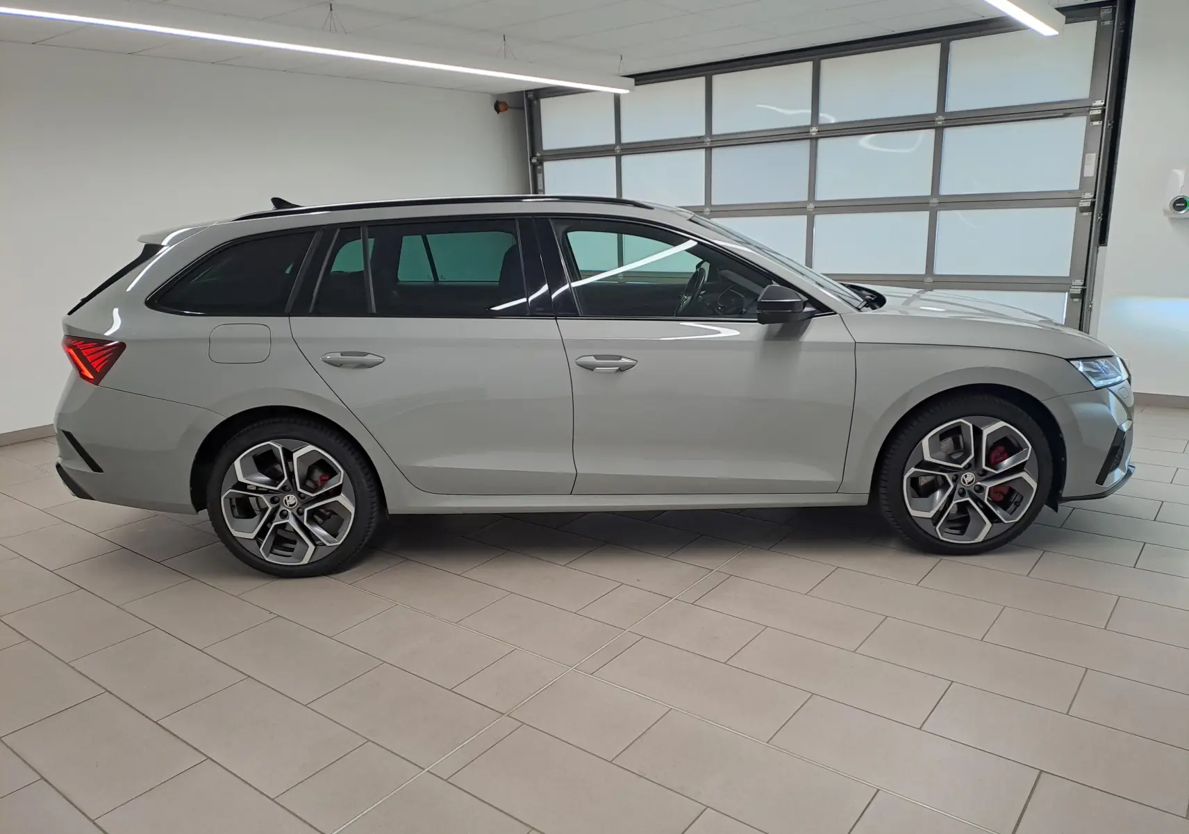 Vue de profil côté gauche d'une Skoda Octavia Combi gris perle avec jantes alliage 19'' anthracite polies en intérieur.