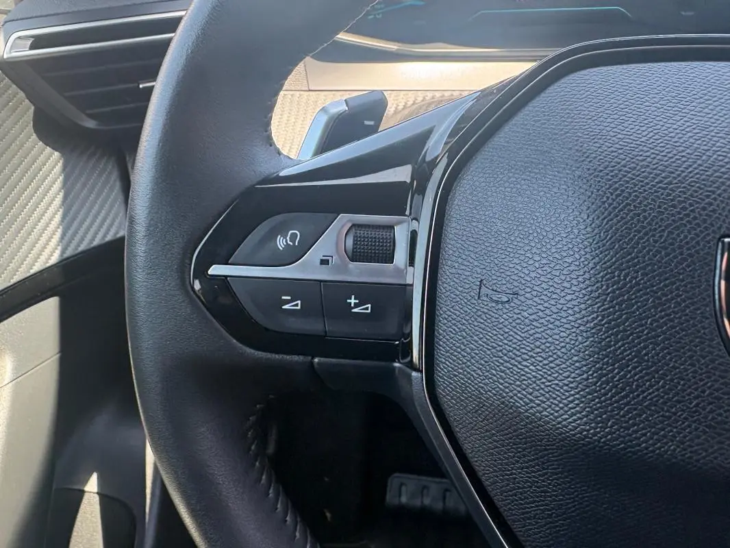 Gros plan sur le volant noir du Peugeot 2008 Hybrid 145 e-DCS6 Style avec commandes audio intégrées.