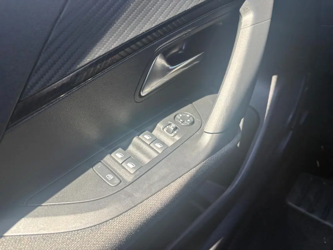 Détail de la porte côté conducteur du Peugeot 2008 gris, montrant les commandes des vitres et rétroviseurs.