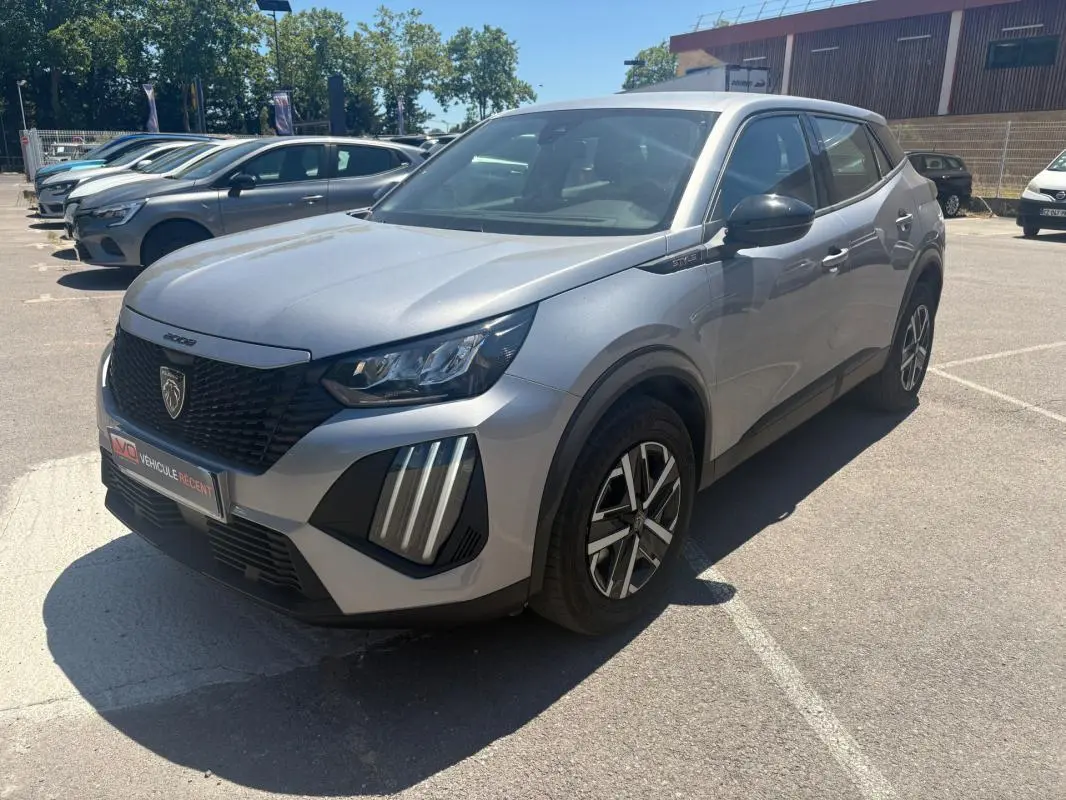 Peugeot 2008 Hybrid gris en 3/4 avant droit, avec calandre noire et feux LED verticaux distinctifs.