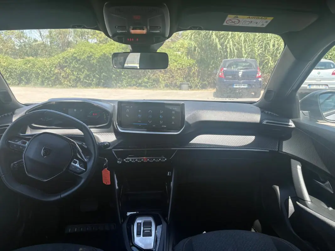 Intérieur du Peugeot 2008 Hybrid 145 Style 2025 vu de face, tableau de bord noir avec écran tactile et volant compact.