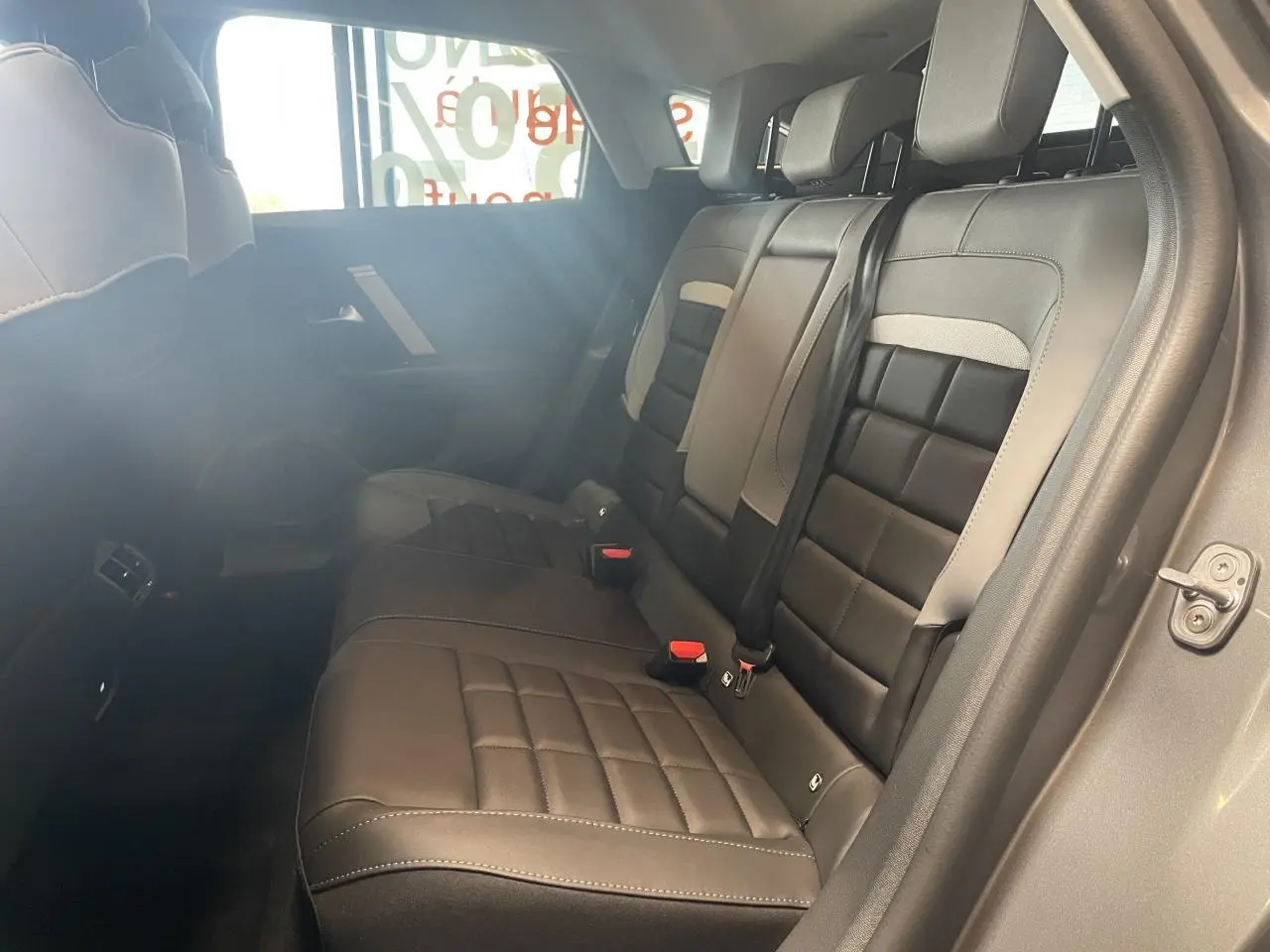 Vue intérieure côté droit des sièges arrière en cuir noir et gris clair de la Citroën C4 hybride 2026.