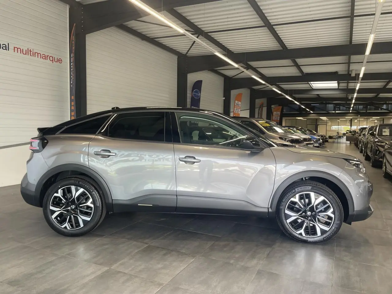 Profil droit d'une Citroën C4 gris métallisé avec toit noir et jantes alliage 18 pouces en intérieur showroom.