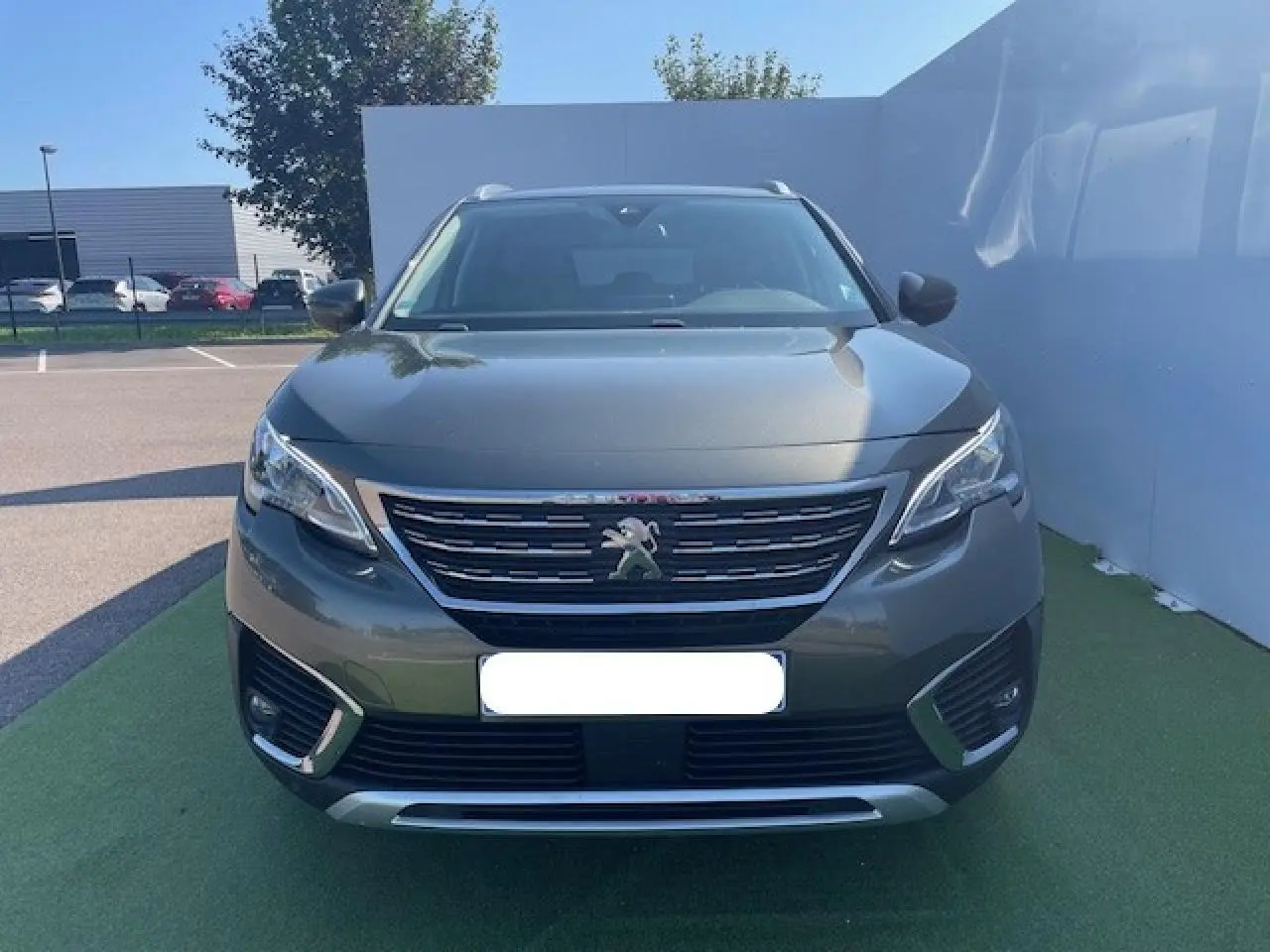 Vue frontale d'un Peugeot 5008 gris amazonite avec calandre chromée et feux LED diurnes intégrés.