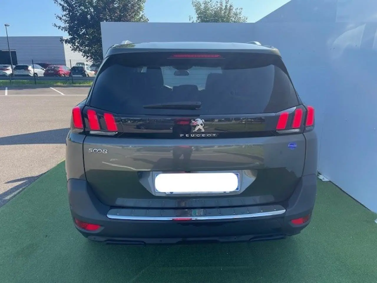 Vue arrière d'un Peugeot 5008 gris Amazonite avec feux arrière à trois griffes rouges et logo lion chromé.