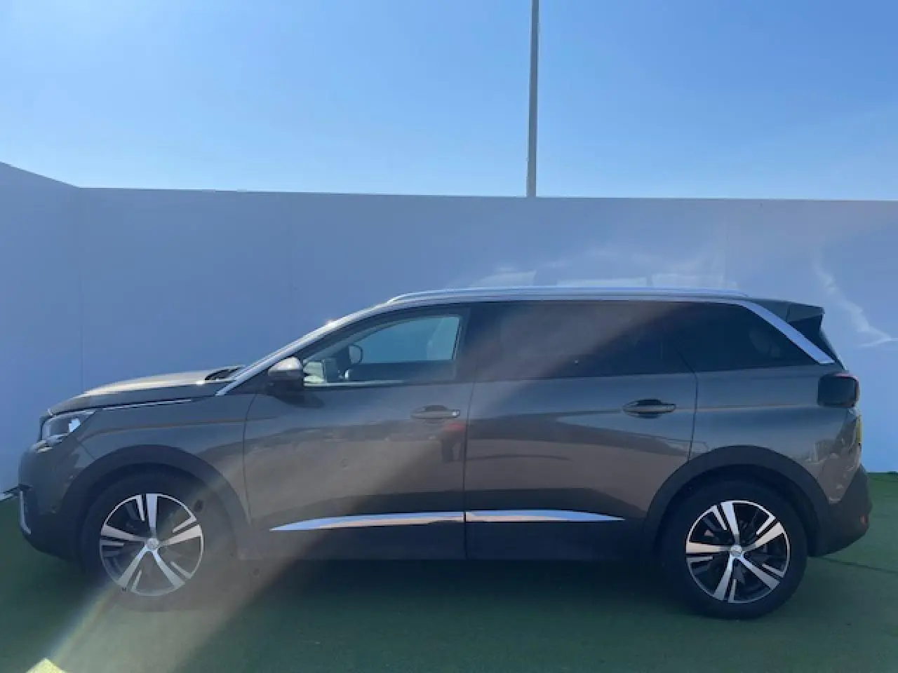 Profil côté gauche d'un Peugeot 5008 gris amazonite avec jantes alliage et vitres surteintées.