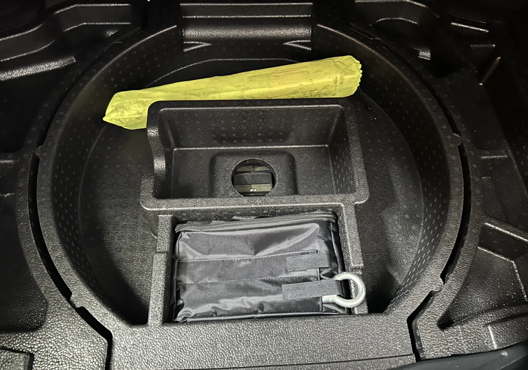Compartiment de rangement sous le coffre du DS4 2024 noir Perla Nera avec kit de secours et outil jaune visible.