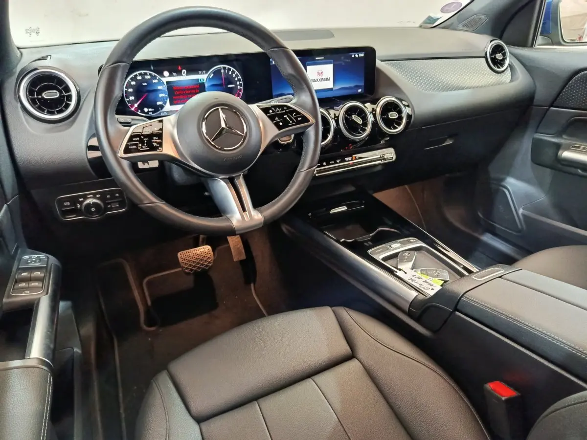 Intérieur avant droit du Mercedes GLA 250 e Business Line 2024, tableau de bord noir avec écran tactile et volant cuir multifonctions.