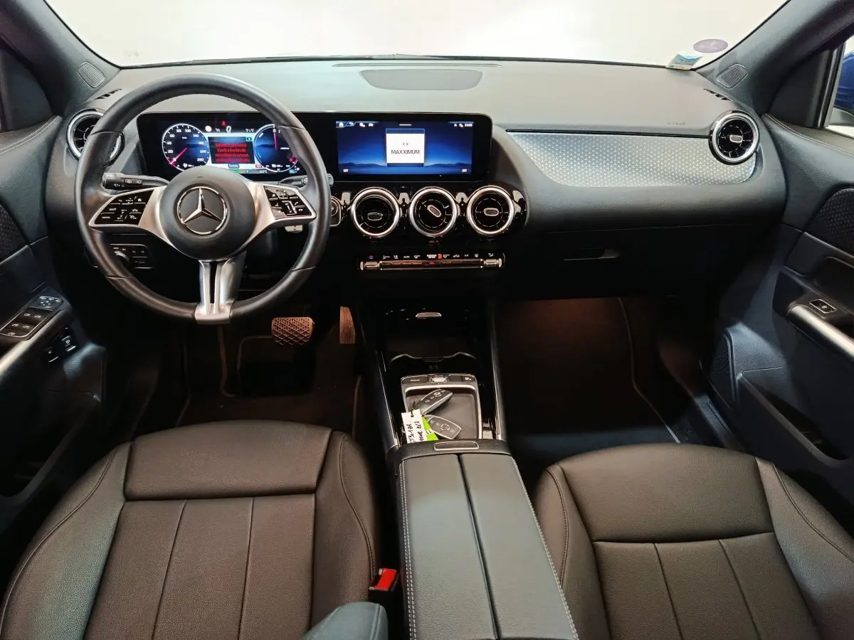 Intérieur noir du Mercedes GLA 250 e 2024 vu de face, tableau de bord avec écran tactile et volant cuir multifonctions.
