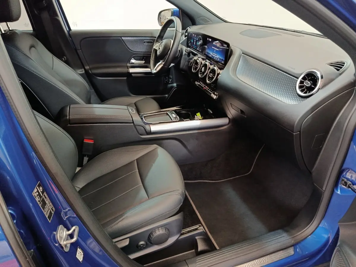 Intérieur côté conducteur du Mercedes GLA 250 e Business Line 2024 bleu, avec tableau de bord numérique et sièges cuir noirs.