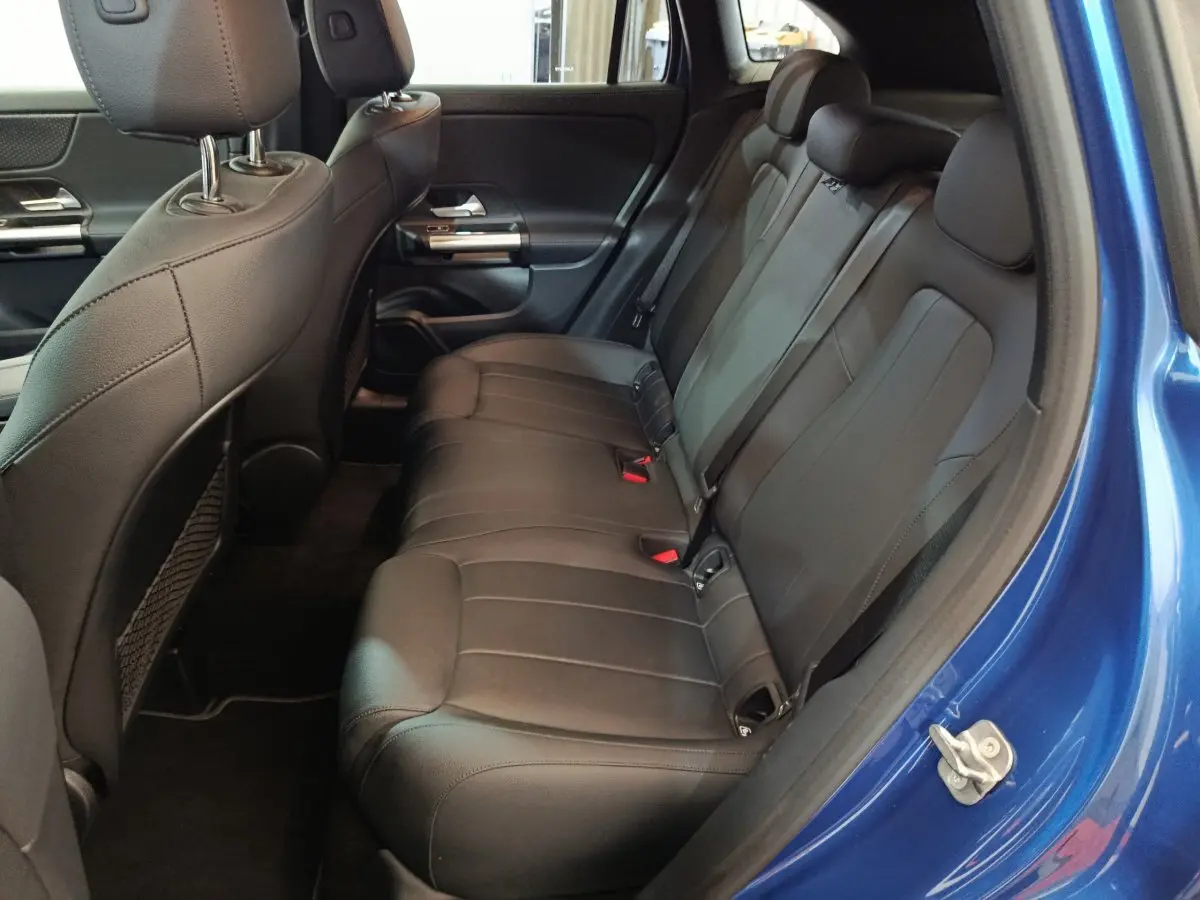 Vue côté droit de l'habitacle arrière d'un Mercedes GLA 250 e bleu avec sièges en cuir noir et ceintures de sécurité.