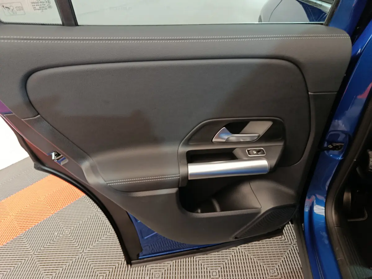 Gros plan sur la porte arrière gauche bleu d'une Mercedes GLA 250 e Business Line avec poignée argentée et bouton de verrouillage.