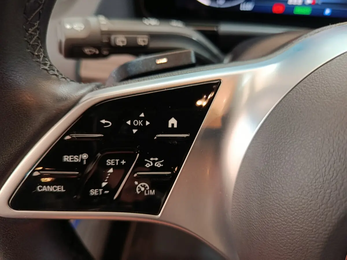 Gros plan sur les commandes multifonctions à gauche du volant cuir du Mercedes GLA 250 e Business Line bleu 2024 hybride.