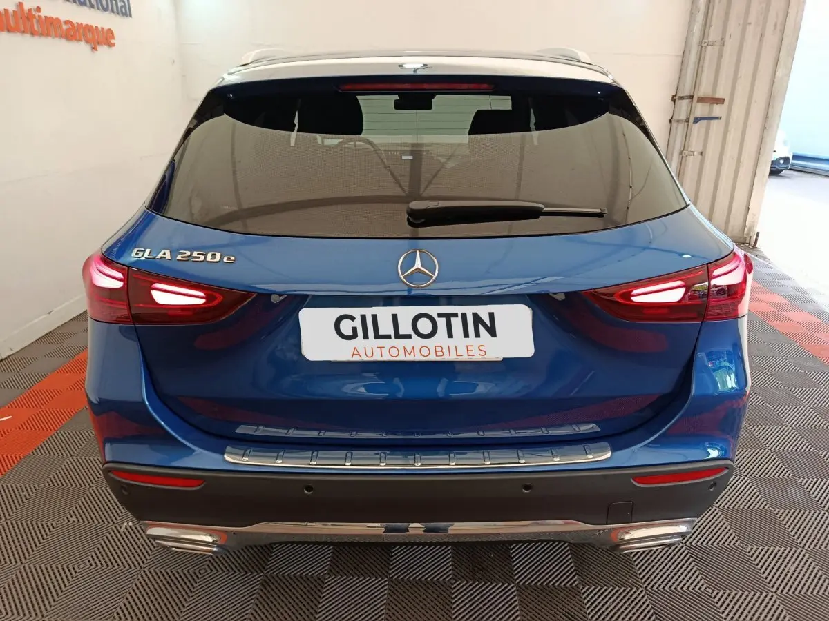 Vue arrière d'un Mercedes GLA 250 e bleu avec feux LED allumés et logo Mercedes visible sur le coffre.