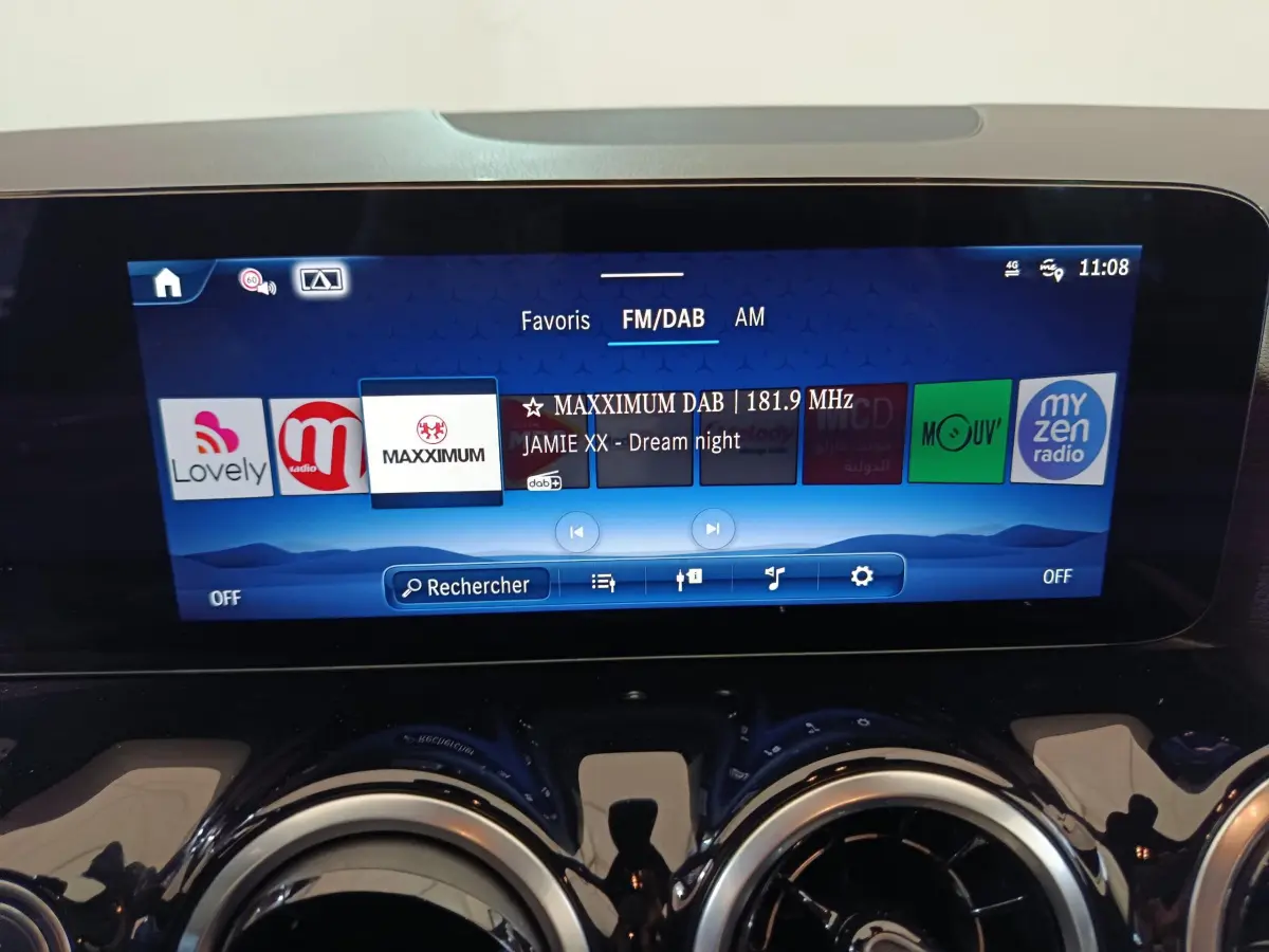 Écran tactile central bleu affichant la radio FM/DAB dans le tableau de bord du Mercedes GLA 250 e 2024.