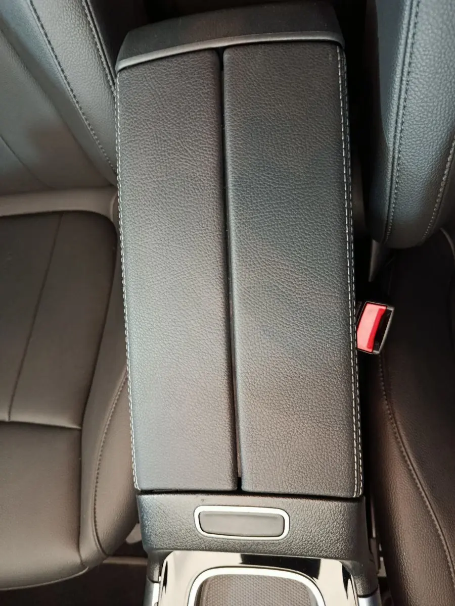 Vue plongeante sur l'accoudoir central en cuir noir et les sièges avant du Mercedes GLA 250 e Business Line 2024.