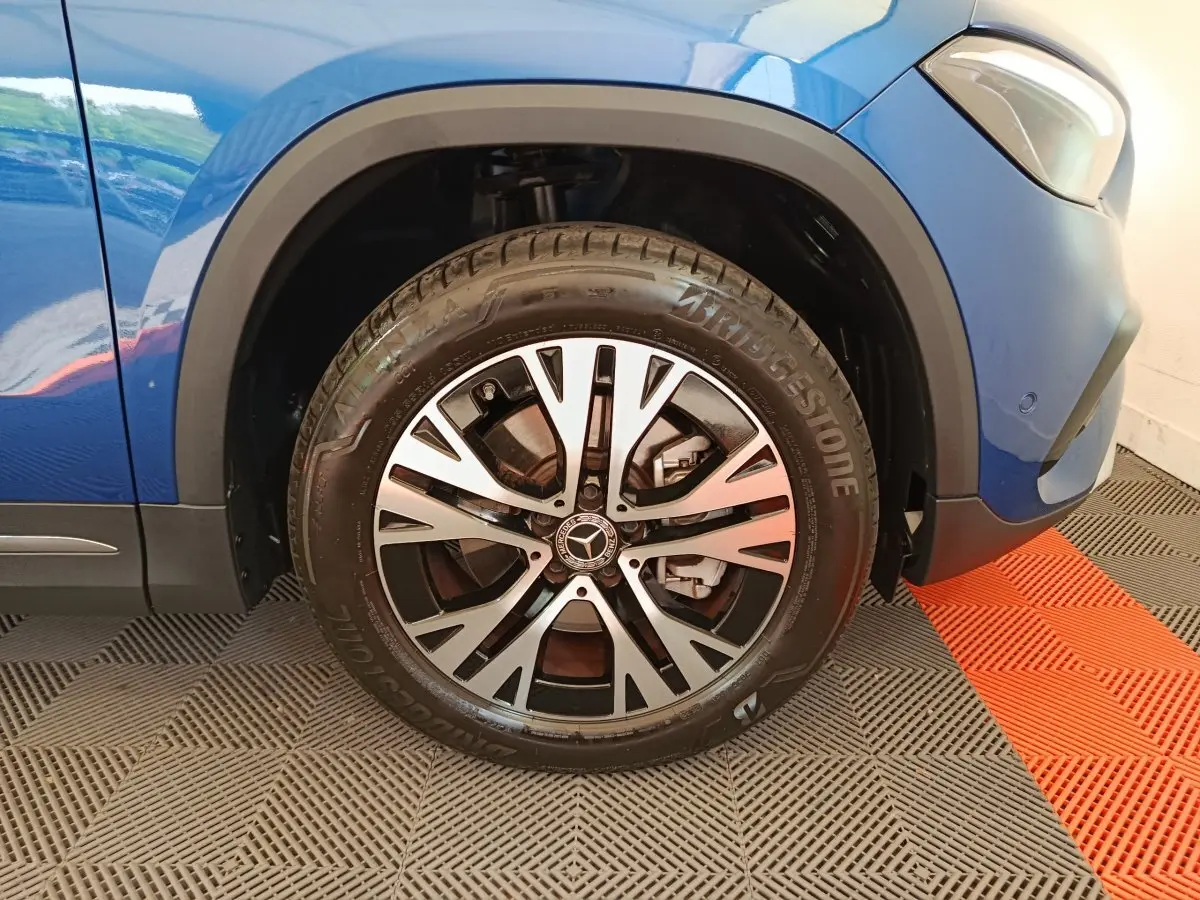 Gros plan sur la roue avant gauche du Mercedes GLA 250 e Business Line bleu avec jante alliage et logo Mercedes au centre.