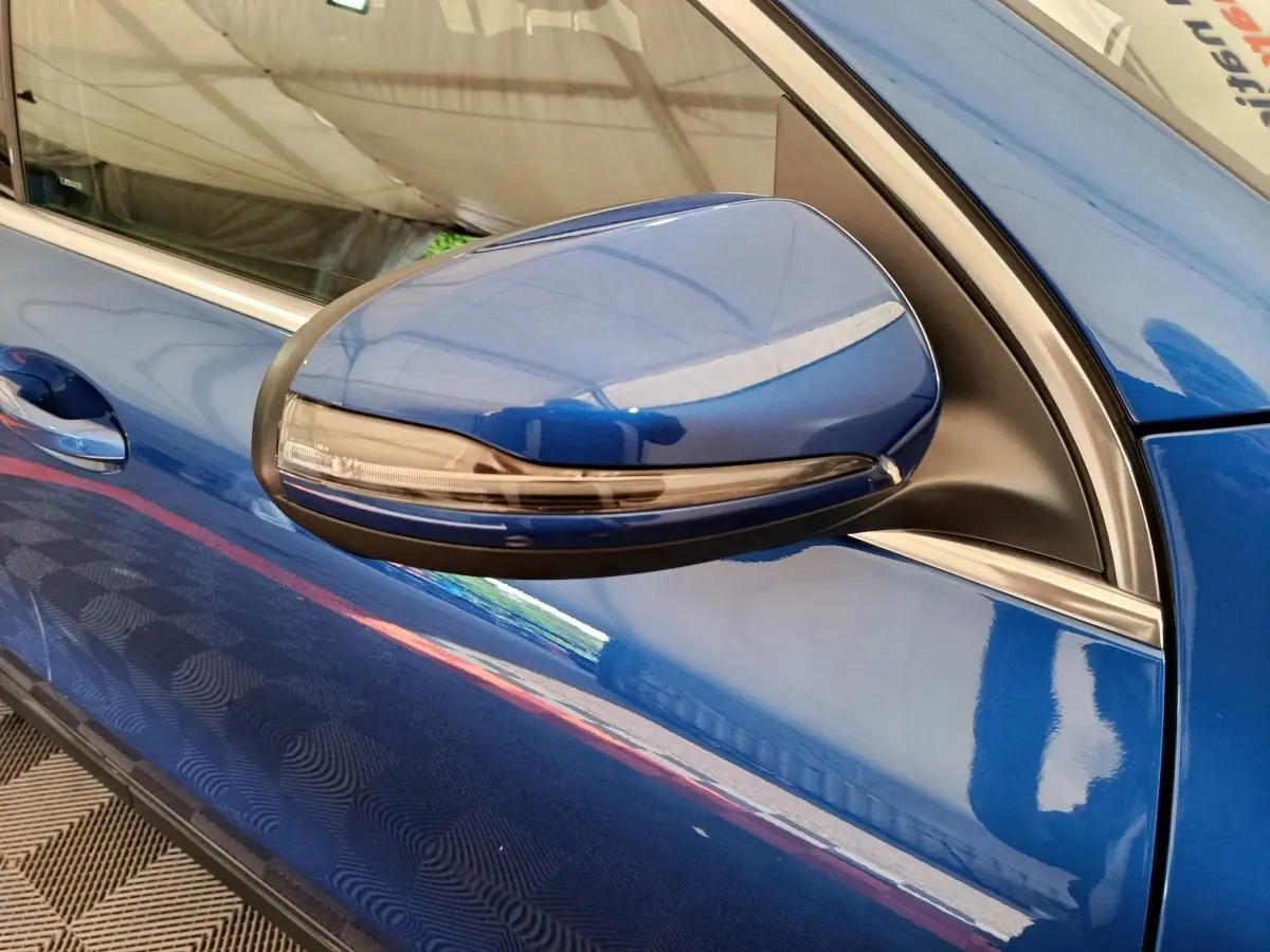Gros plan sur le rétroviseur côté gauche bleu métallisé d'une Mercedes GLA 250 e Business Line 2024.
