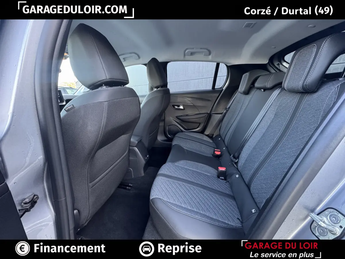 Vue intérieure arrière côté droit de la Peugeot 208 Hybrid 110 Allure 2025, sièges tissu gris et cuir noir.