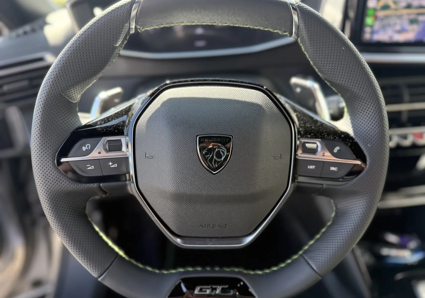 Vue rapprochée du volant cuir noir avec surpiqûres vertes et logo Peugeot sur le Peugeot 2008 Hybrid 145ch GT 2025.