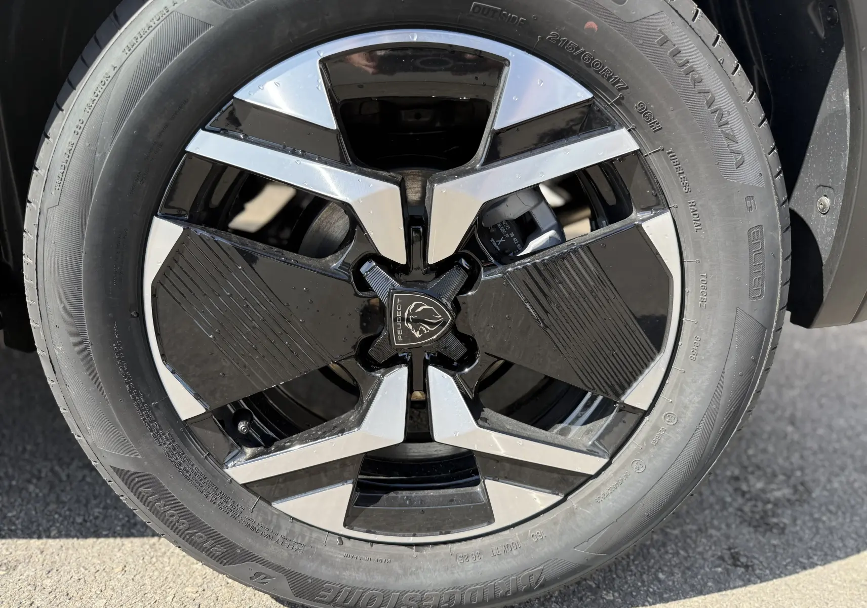 Gros plan sur la jante avant droite noire et argentée du Peugeot 2008 Hybrid 145ch gris Artense toit noir 2025.