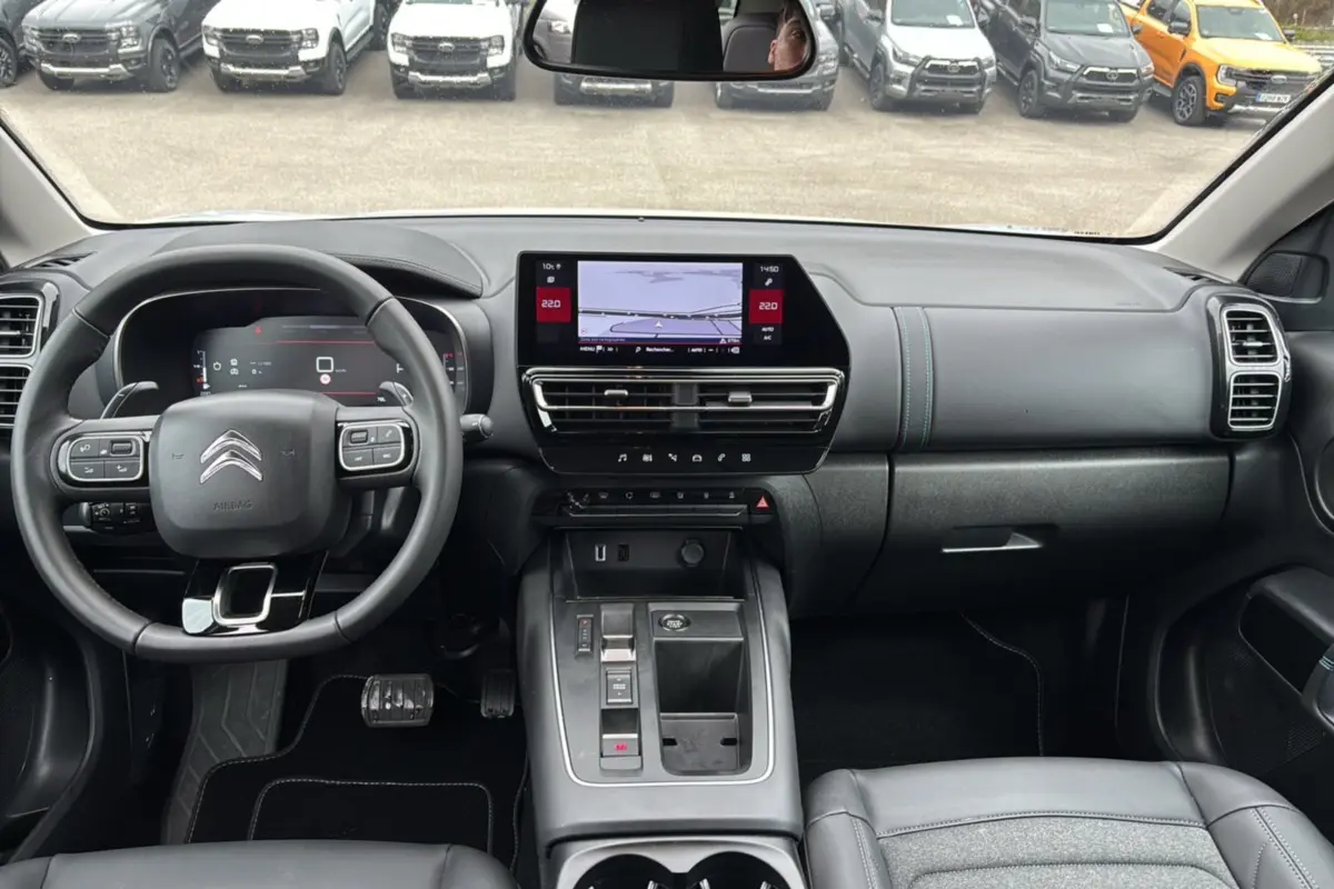 Vue intérieure du poste de conduite du Citroën C5 Aircross Hybrid blanc, avec tableau de bord numérique et écran central tactile.