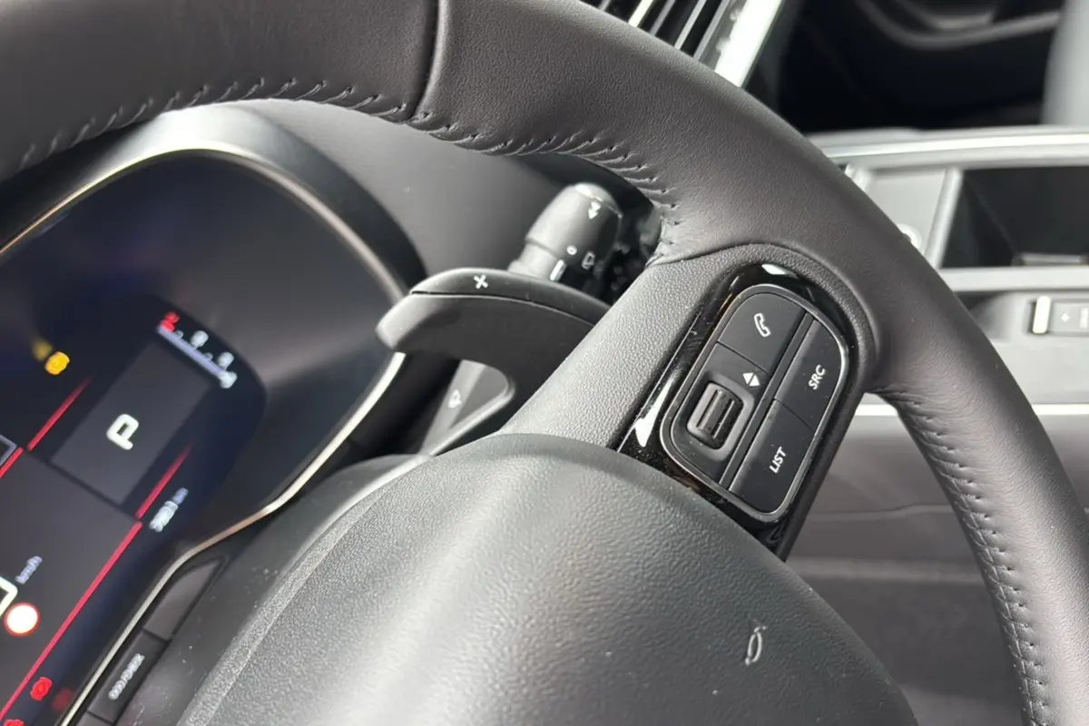 Gros plan sur le volant cuir noir du Citroën C5 Aircross Hybrid 145, avec commandes multifonctions visibles côté droit.