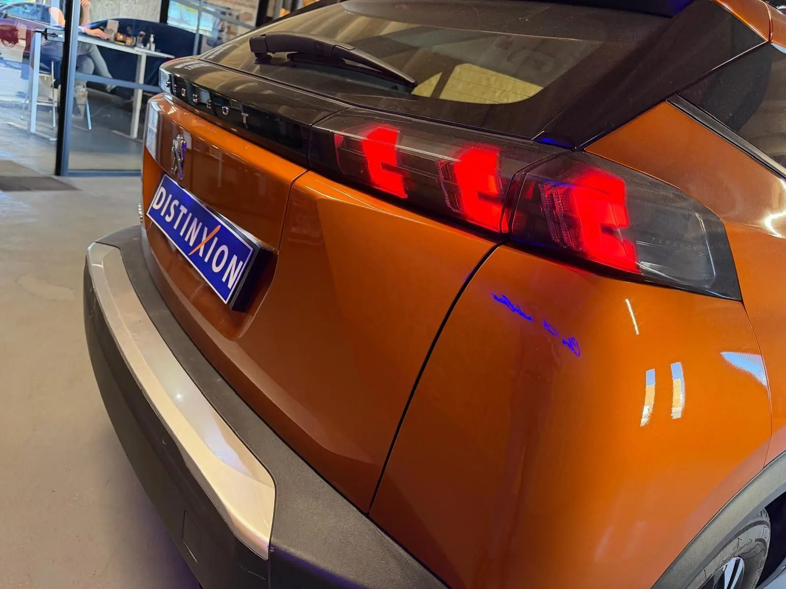 Vue 3/4 arrière droite du Peugeot 2008 orange avec feux arrière LED en forme de griffes et becquet noir brillant.