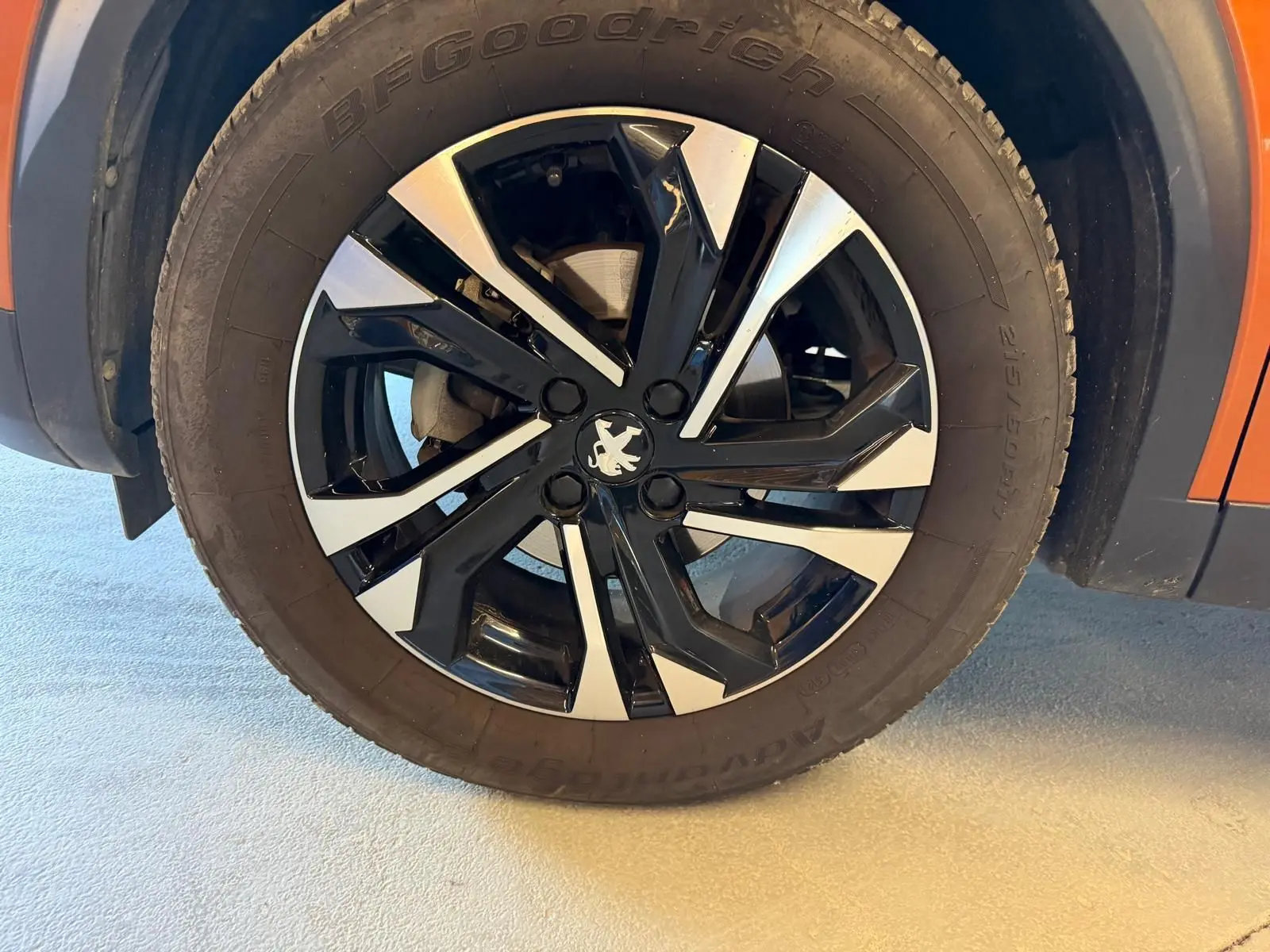 Gros plan sur la jante alliage 17'' bi-ton noir et argent du côté gauche d’un Peugeot 2008 orange.