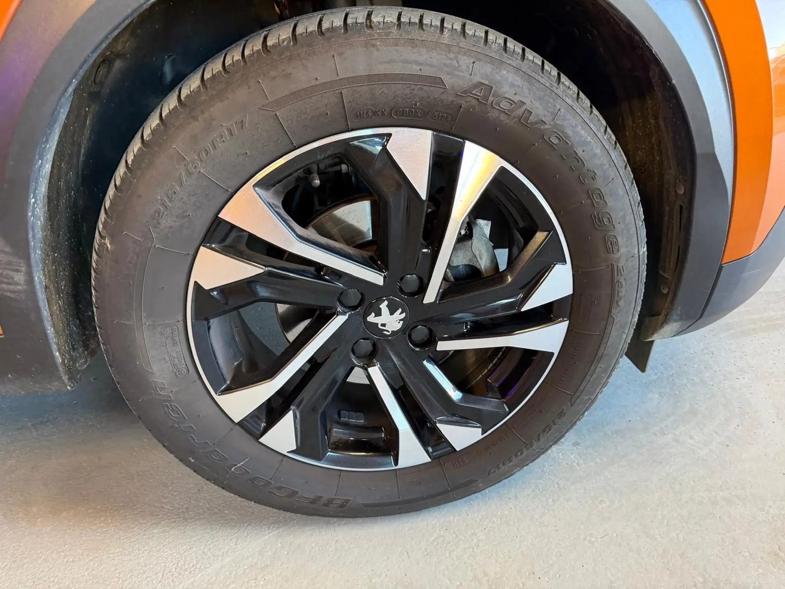 Gros plan sur la jante alliage 17'' bi-ton noir et argent du côté avant gauche d’un Peugeot 2008 orange.