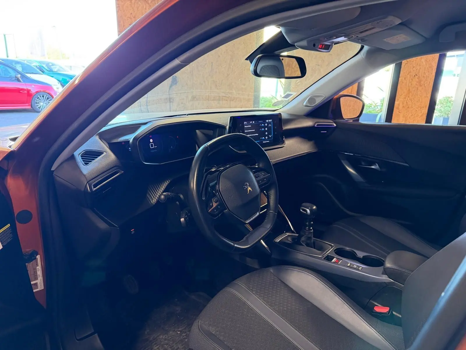 Intérieur de la Peugeot 2008 orange vue côté conducteur, volant compact, tableau de bord numérique et boîte manuelle.