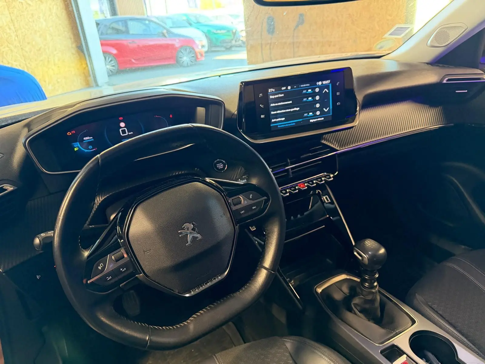 Vue intérieure de face du tableau de bord et volant compact noir du Peugeot 2008 1.5 BlueHDi 100 Allure avec écran tactile central.