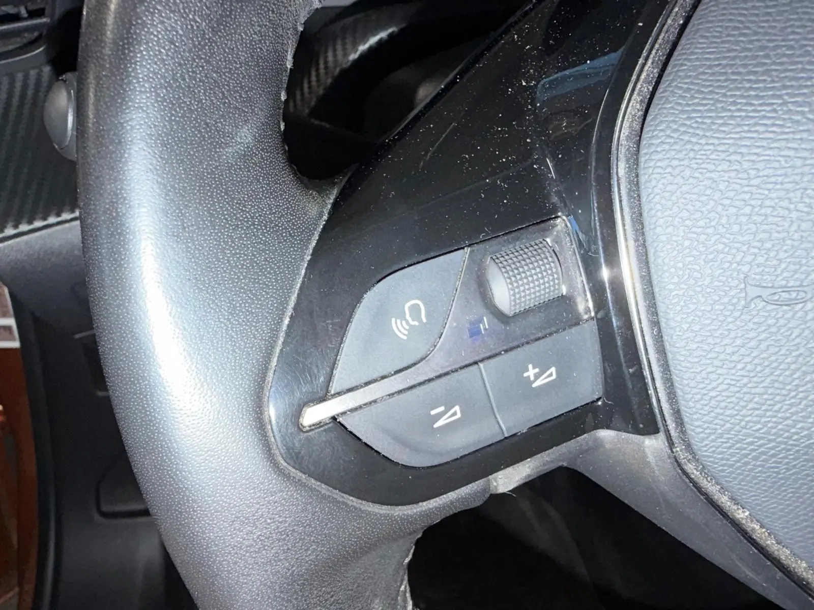 Gros plan sur les commandes multimédia noires du volant cuir du Peugeot 2008 Orange Fusion 2020.