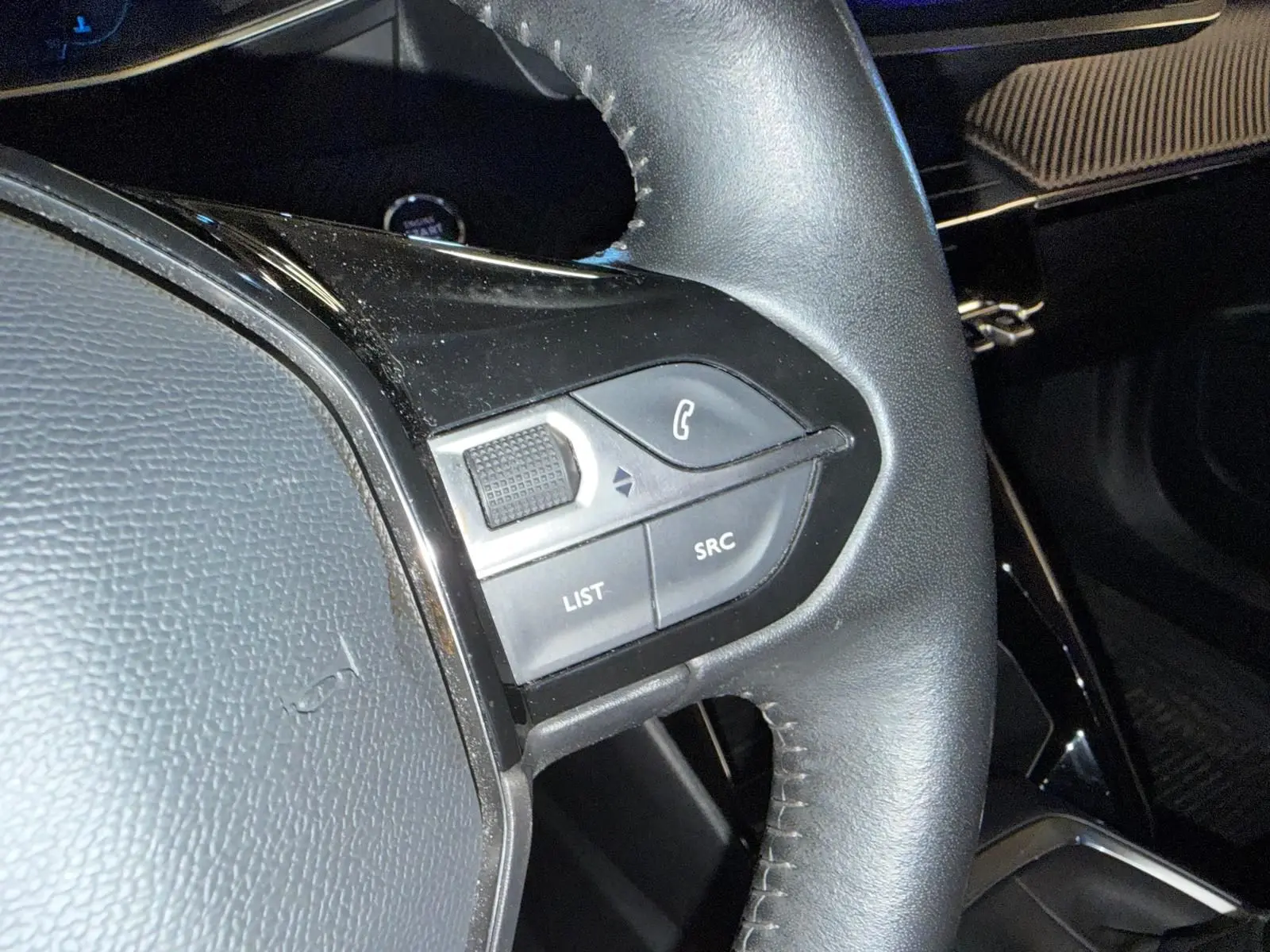 Gros plan sur le volant cuir noir du Peugeot 2008 2020 avec commandes multimédia à gauche.