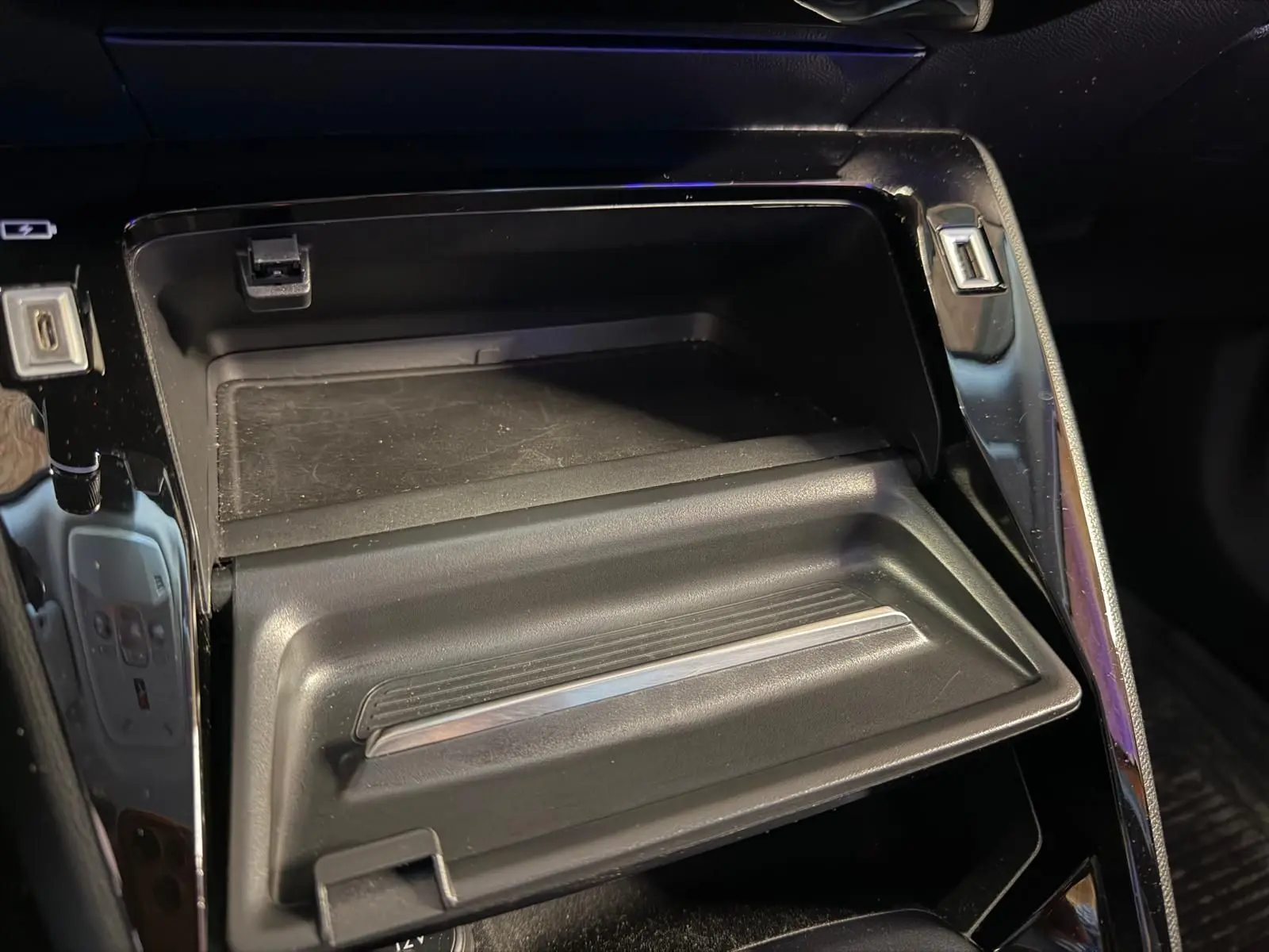 Gros plan sur la console centrale noire brillante du Peugeot 2008 1.5 BlueHDi 100 Allure 2020, avec rangement ouvert.