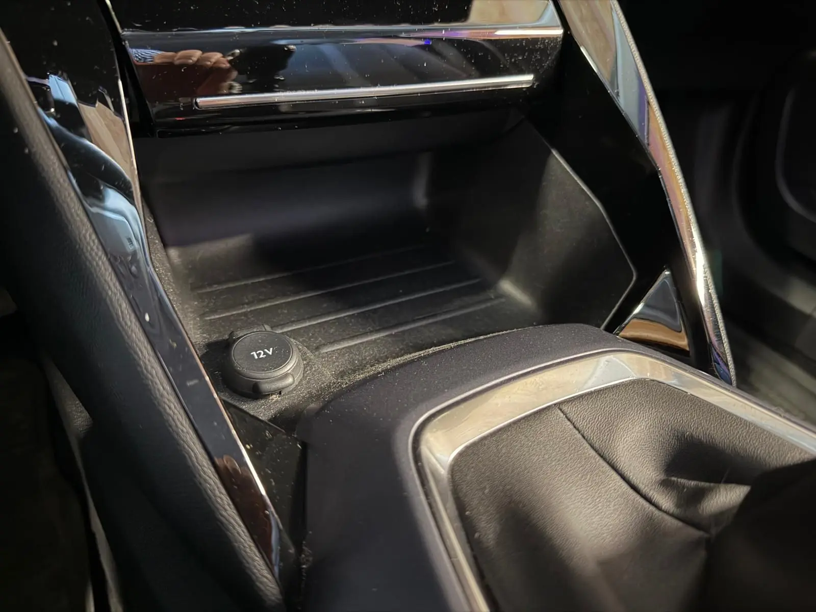 Gros plan de la console centrale noire du Peugeot 2008 1.5 BlueHDi 100 Allure avec prise 12V et habillage chromé.
