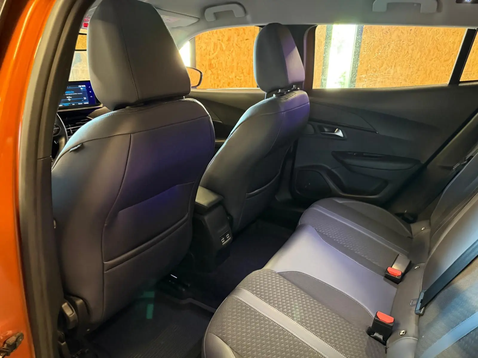 Vue intérieure arrière droite de la banquette noire et grise du Peugeot 2008 orange, avec dossiers des sièges avant visibles.