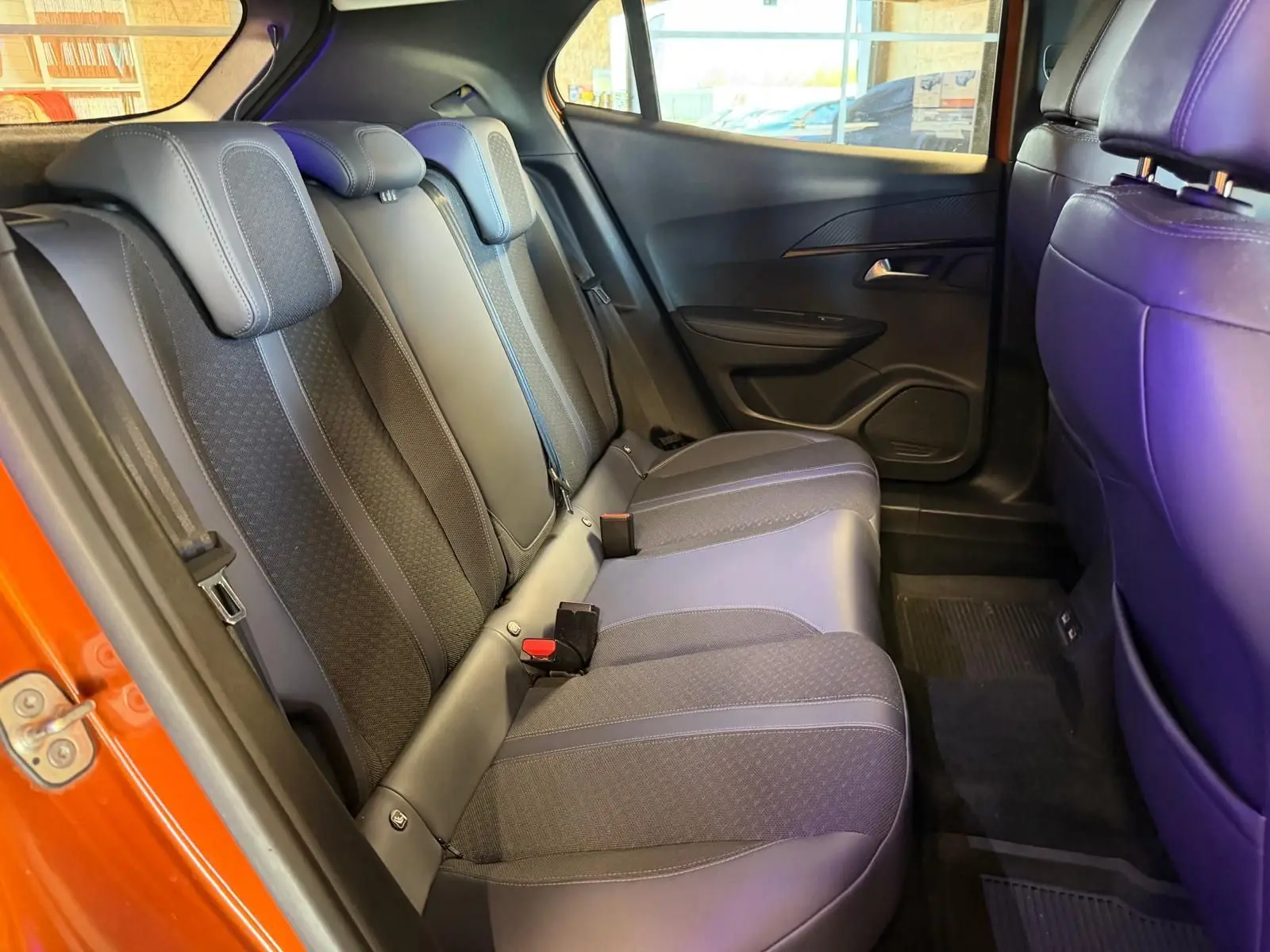 Vue intérieure de la banquette arrière du Peugeot 2008 orange, avec sellerie tissu et cuir gris foncé.