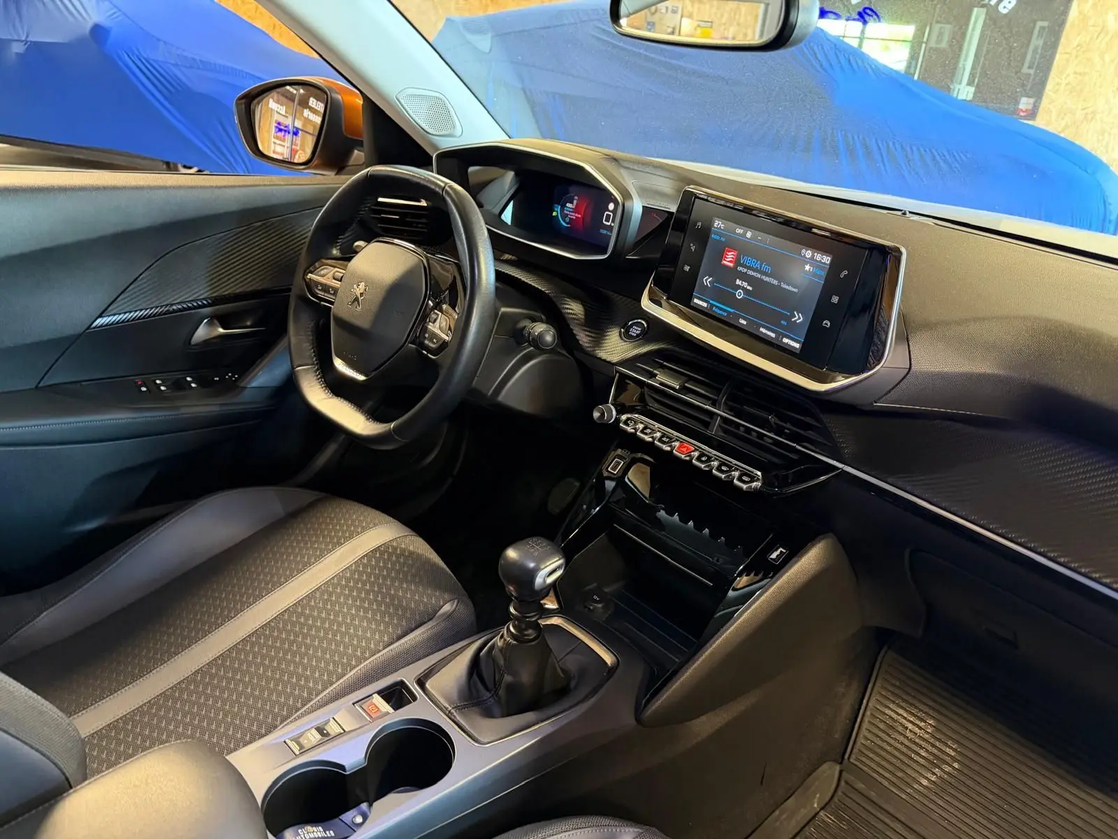 Intérieur avant droit du Peugeot 2008 orange 2020, volant compact, écran tactile et levier de vitesse manuel visibles.