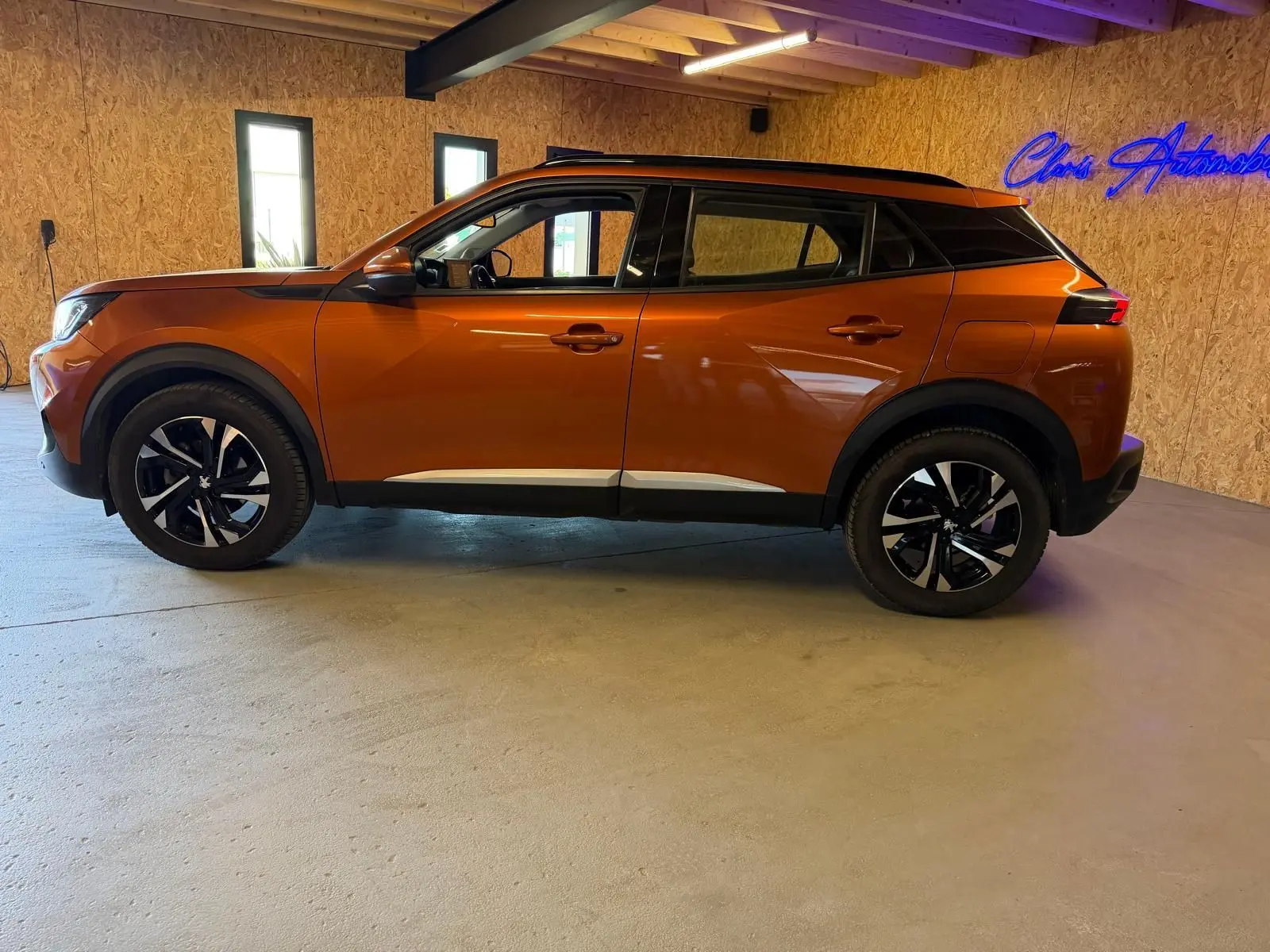 Peugeot 2008 orange vue de profil côté gauche, avec jantes alliage bi-ton et toit noir contrasté.